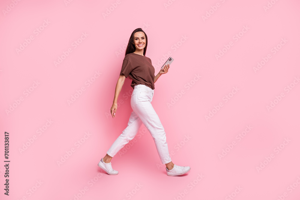 Full length photo of walking business lady make a blog in social networks working remotely using phone isolated on pink color background