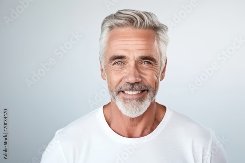 Portrait of handsome mature man in white t-shirt. Isolated on grey background