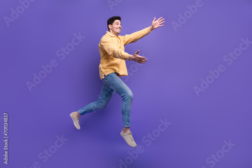 Full size photo of attractive young man running stretch hands want hug dressed stylish yellow clothes isolated on purple color background