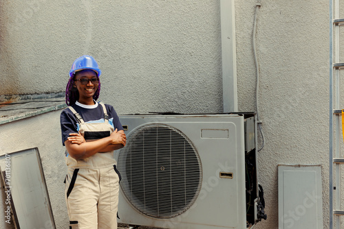Portrait of cheerful knowledgeable professional proud of work done, standing in front of fixed hvac system. Specialist contracted by client happy with smooth servicing of internal condenser parts photo