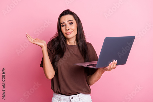 Photo of young funny woman working indifferent shrug shoulders ignoring boss messages using laptop isolated on pink color background photo
