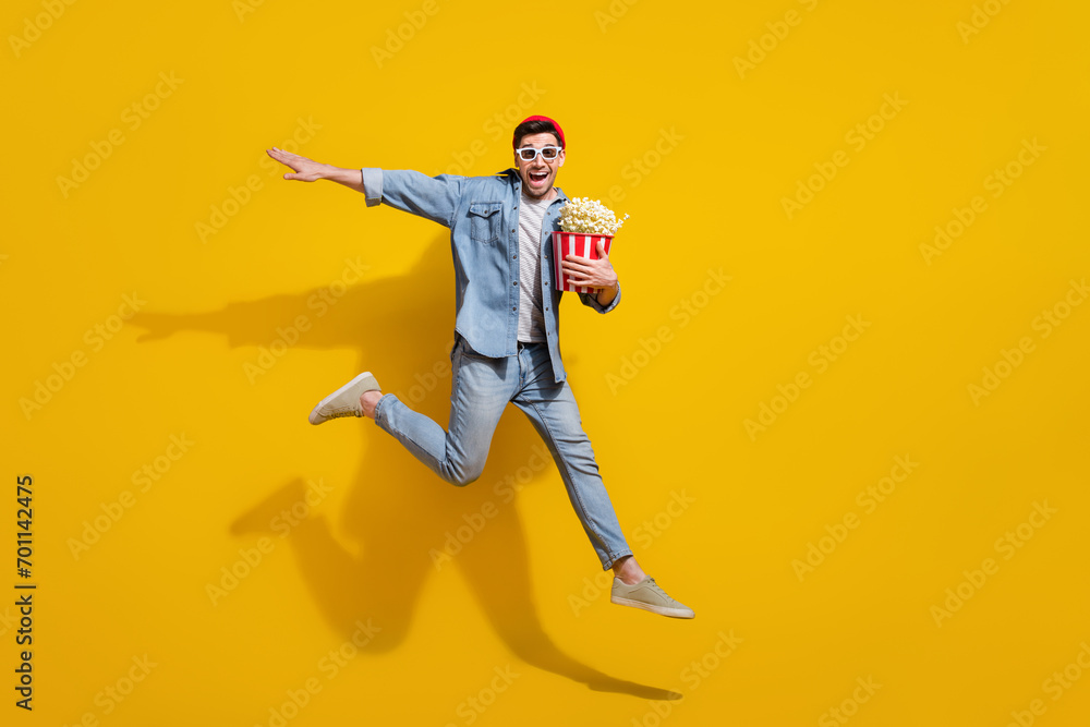 Full length photo of cool carefree man dressed jeans shirt eating pop corn watching vr movie empty space isolated yellow color background