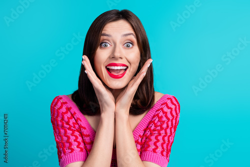 Photo of overjoyed impressed woman with straight hairdo dressed knitwear top hands on cheeks staring isolated on blue color background