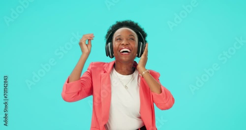 Music, dancing and black woman with headphones to listen in studio isolated on a blue background mockup space. Radio, streaming and happy person hearing podcast, sound or audio for moving with energy photo