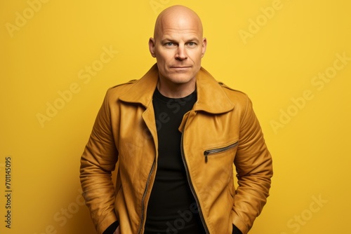 Portrait of a bald man in a yellow leather jacket on a yellow background