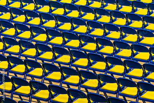 Rows of blue and yellow chairs forming a. geometric pattern.