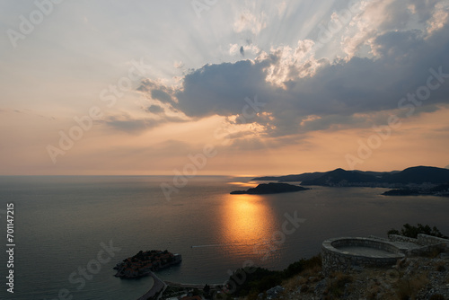 Orange sunset over the mountains and the island of Sveti Stefan. Montenegro