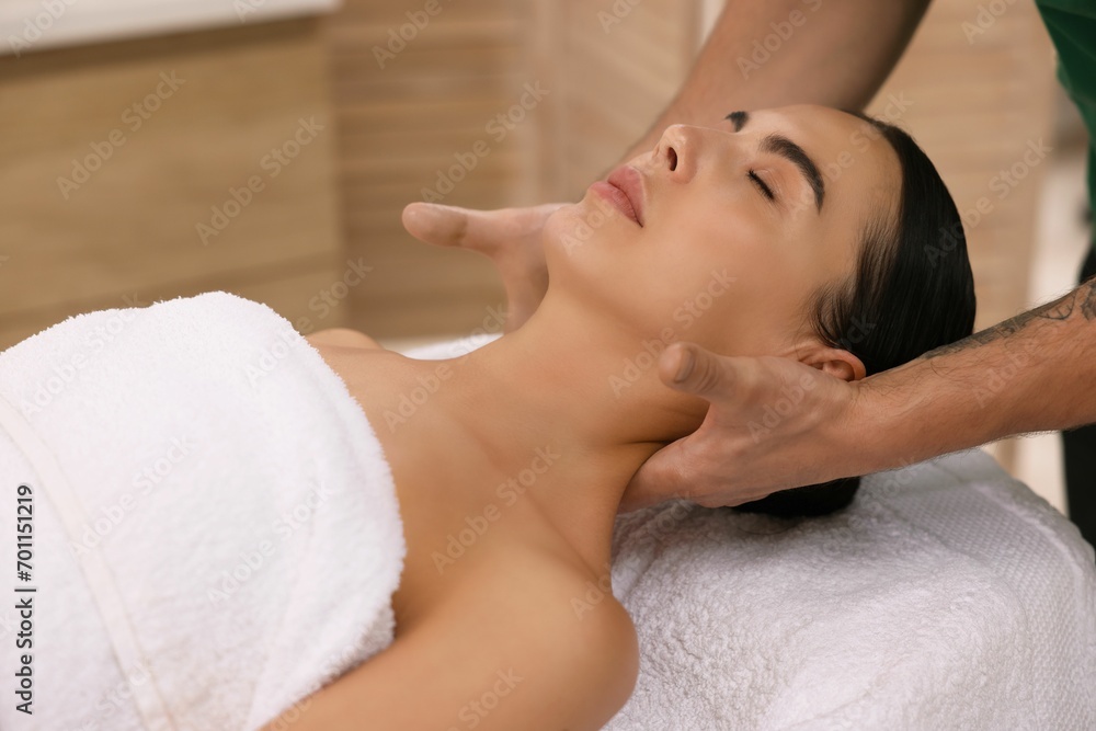 Woman receiving professional neck massage on couch indoors