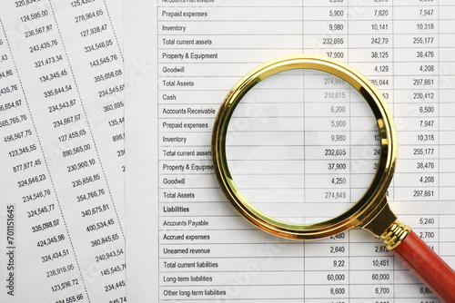 Magnifying glass on accounting documents with data  top view