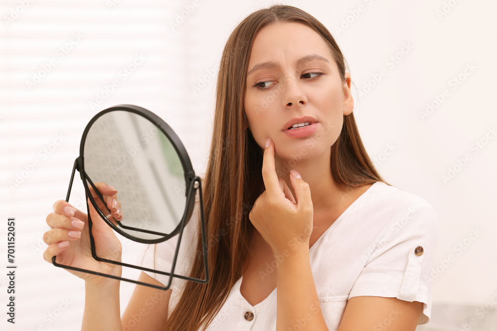 Woman with skin problem looking at mirror indoors Woman with skin problem looking at mirror indoors