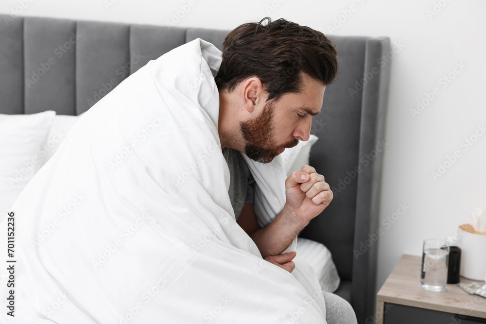 Fototapeta premium Sick man coughing on bed at home. Cold symptoms