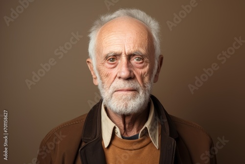 Portrait of a senior man with white beard and brown jacket. Studio shot.