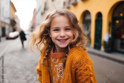 Portrait of a cute little girl with long blond hair in a yellow sweater
