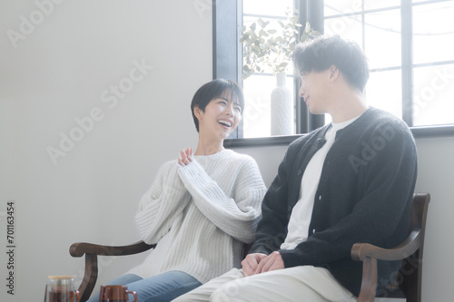 A happy, smiling couple relaxing in a beautifully backlit room or cafe, smiling broadly.