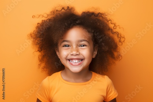 Portrait of a cute little african american girl with curly hair on orange background © Loli