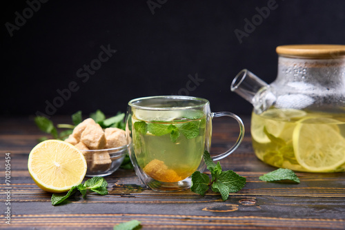 natural organic herbal tea with lemon and mint in glass teapot on a wooden table