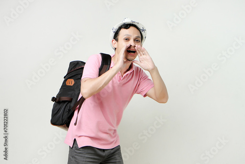 Asian man backpacker shouting outloud. digital nomad and travelling concept. on isolated background photo