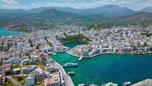 Aerial panoramic view of Agios Nikolaos City on Crete Island in Greece in 4K. Sunny summer City day on Mediterranean Island with turquoise water. Paralia Kitroplatia, Ammos, Yachting Sailing Cruises photo