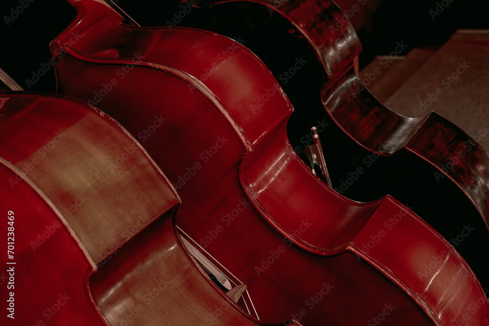  three large double basses standing on a theater stage - obrazy, fototapety, plakaty 