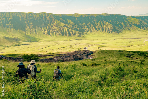 A group of hikers against mountains and valleys at Mount Ol Doinyo Lengai in Tanzania photo