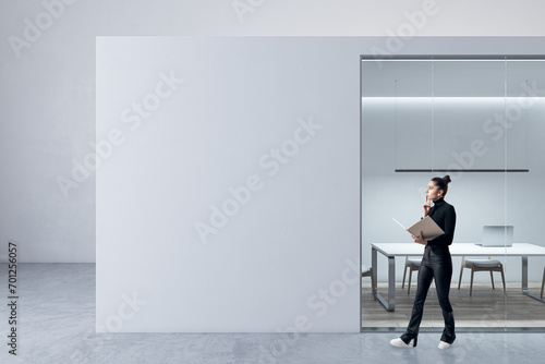Blurry happy young female walking in modern light concrete and glass office box interior with mock up place on walls and wooden floors. Designer concept.