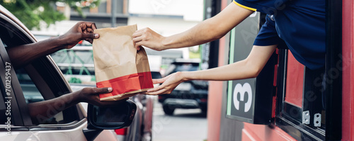 Hand Man in car receiving coffee in drive thru fast food restaurant. Staff serving takeaway order for driver in delivery window. Drive through and takeaway for buy fast food for protect covid19. photo