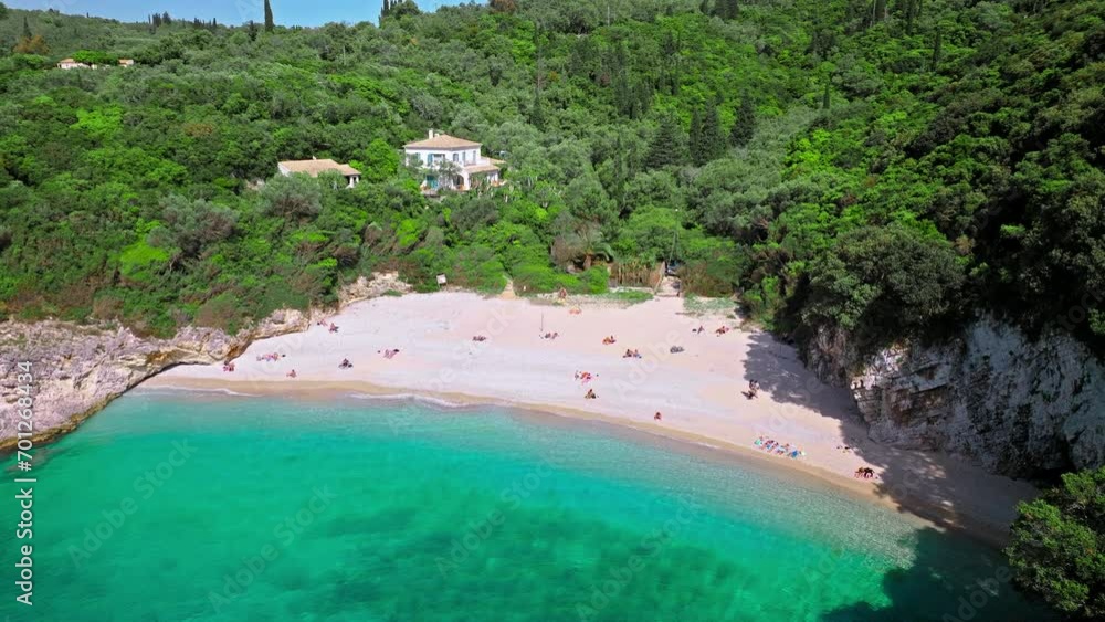Aerial view of Rovinia Beach with tourists enjoying vacation with dreamy crystal-clear turquoise waters. View of mesmerizing white-pebble shore mixed with sand and green forest in the background. Aerial view of Rovinia Beach with tourists enjoying vacation with dreamy crystal-clear turquoise waters. View of mesmerizing white-pebble shore mixed with sand and green forest in the background.