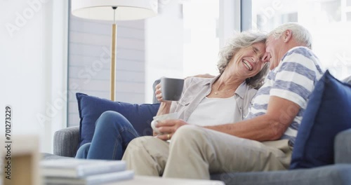 Love, happy and senior couple hug on a sofa with coffee, connection and romance at home together. Support, gratitude and old people embrace in a living room enjoying relationship, tea and retirement photo