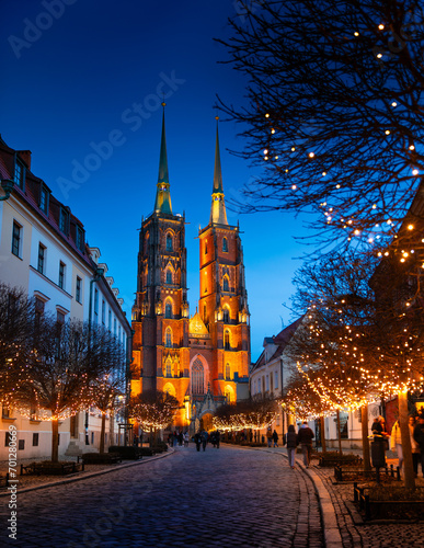 Street with cobblestone road, lights on trees, St. John the Baptist Cathedral with two spiers in the old historical city center, Tumski Island, Wroclaw, Poland photo