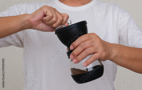 Closeup: Hands of a woman who is grinding coffee beans manually photo
