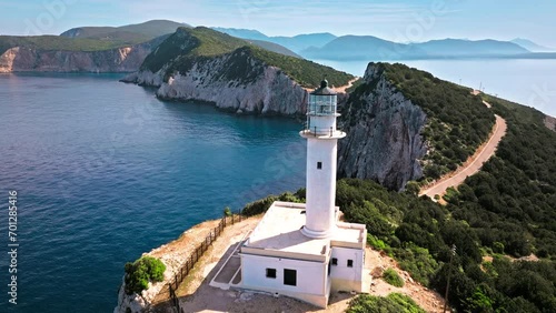 Aerial view of Phare de Akrotiri Lefkada Lighthouse in Cape Doukato. View from above of a white tower on a rocky cliff by the edge of the coast in Lefkada surrounded by emerald-blue waters. photo