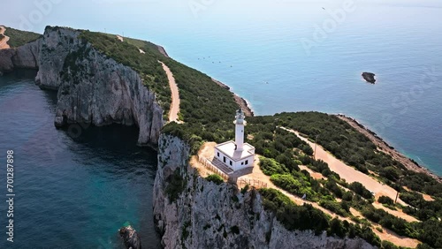 Aerial view of Phare de Akrotiri Lefkada Lighthouse in Cape Doukato. View from above of a white tower on a rocky cliff by the edge of the coast in Lefkada surrounded by emerald-blue waters. photo