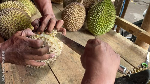Street merchant cut open and sell flesh of fresh durian on a wood table photo
