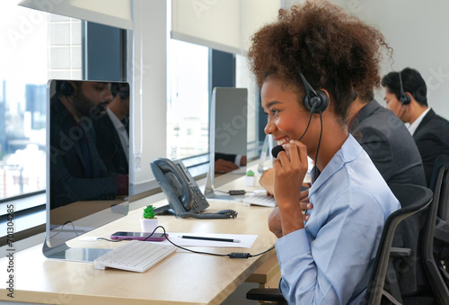 a young african american female using headsets to communicate and service customer in call centre,businesswoman operator agent is answering phone online in modern office