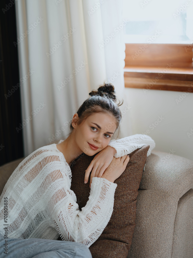 Woman in sweater and home pants relaxing lying on the couch at home, cozy day off in comfort, real lifestyle with a smile. Woman in sweater and home pants relaxing lying on the couch at home, cozy day off in comfort, real lifestyle with a smile.