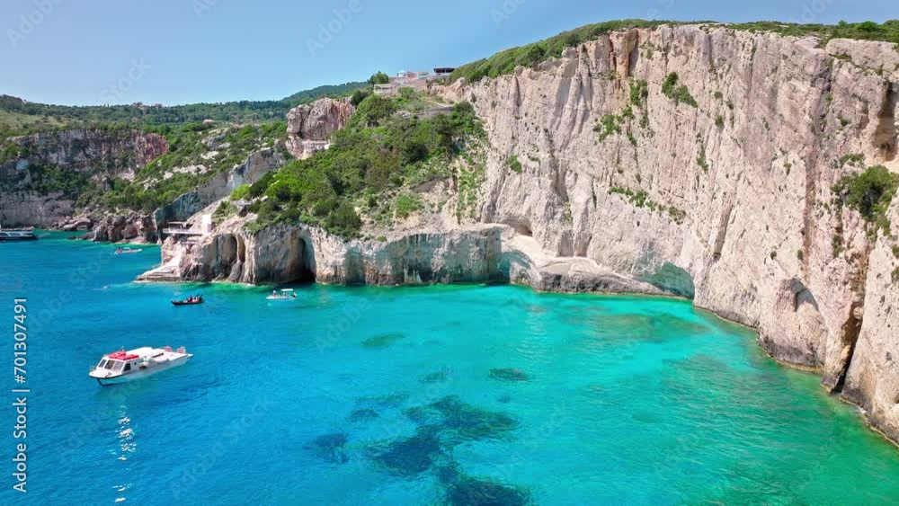 Aerial view of tourists on vacation on a cruise ship at Blue Natural Caves and arches in Zakynthos, Greece. Turquoise transparent blue water, Tourist attraction accessible by boats on Greek Islands. Aerial view of tourists on vacation on a cruise ship at Blue Natural Caves and arches in Zakynthos, Greece. Turquoise transparent blue water, Tourist attraction accessible by boats on Greek Islands.