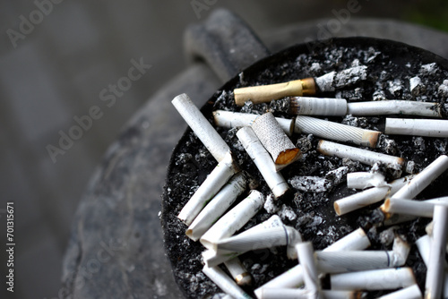 An ashtray for cigarette butts on the street. Smoked cigarettes in the trash.