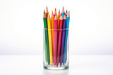 Colored pencils stand in a glass with the point upwards on a white background