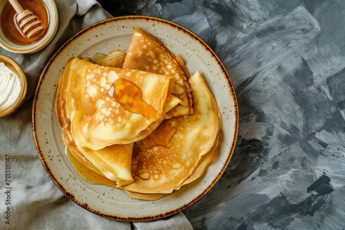 Crepes (thin pancakes) with honey. Tasty morning breakfast on a grey background