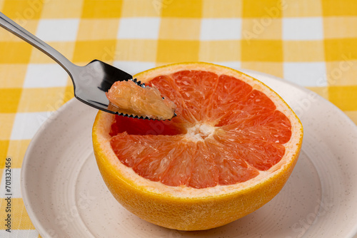 Sliced grapefruit on plate with serrated spoon. Organic fruit, healthy diet and nutrition concept.