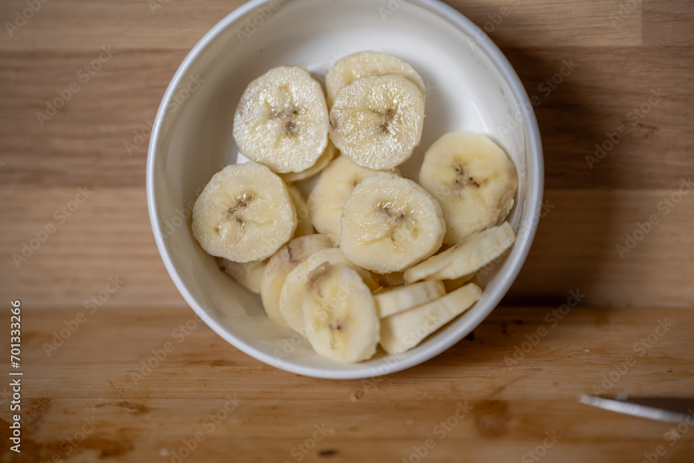 tranches de bananes dans un ramequin blanc sur un plan de travail en bois tranches de bananes dans un ramequin blanc sur un plan de travail en bois