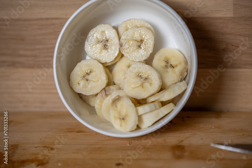 tranches de bananes dans un ramequin blanc sur un plan de travail en bois