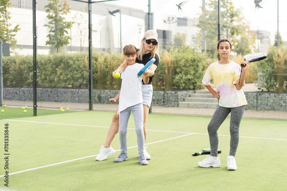 Active young woman practicing Padel Tennis with group of players in the tennis court outdoors