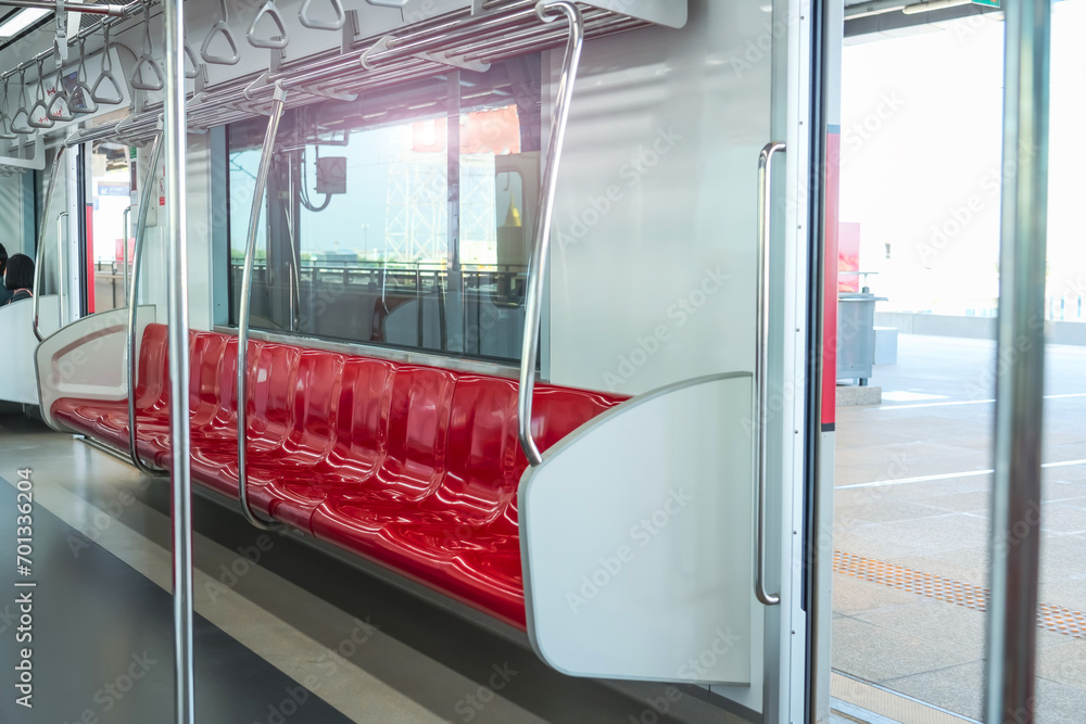 Interior of a passenger car of a commuter train. Red plastic seats and chrome handrails inside an electric train carriage car Interior of a passenger car of a commuter train. Red plastic seats and chrome handrails inside an electric train carriage car
