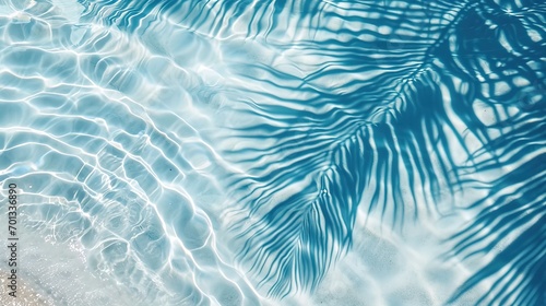 palm leaf shadow on blue water waves, vacation and beauty care with copy space photo
