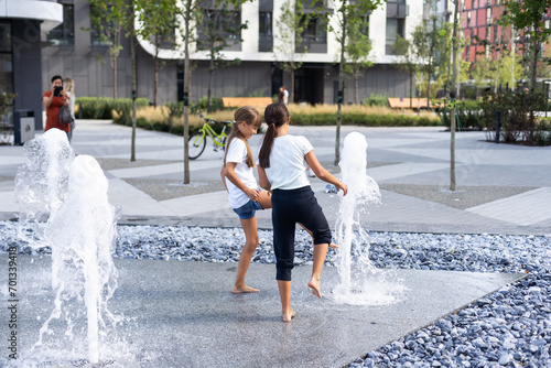 Cute young sisters playing in fountains. Children having fun with water on sunny summer day. Active leisure for kids. photo
