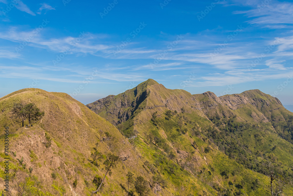 Green yellow mountains and beautiful sky clouds under the blue sky.