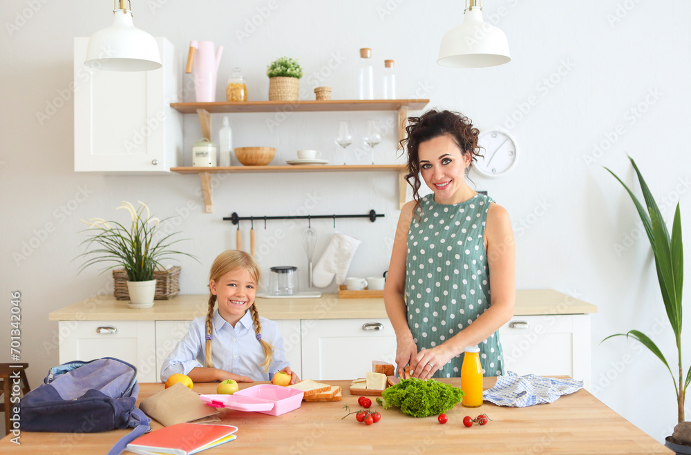 Beautiful brunette mother and her daughter packing healthy lunch and preparing school bag Beautiful brunette mother and her daughter packing healthy lunch and preparing school bag