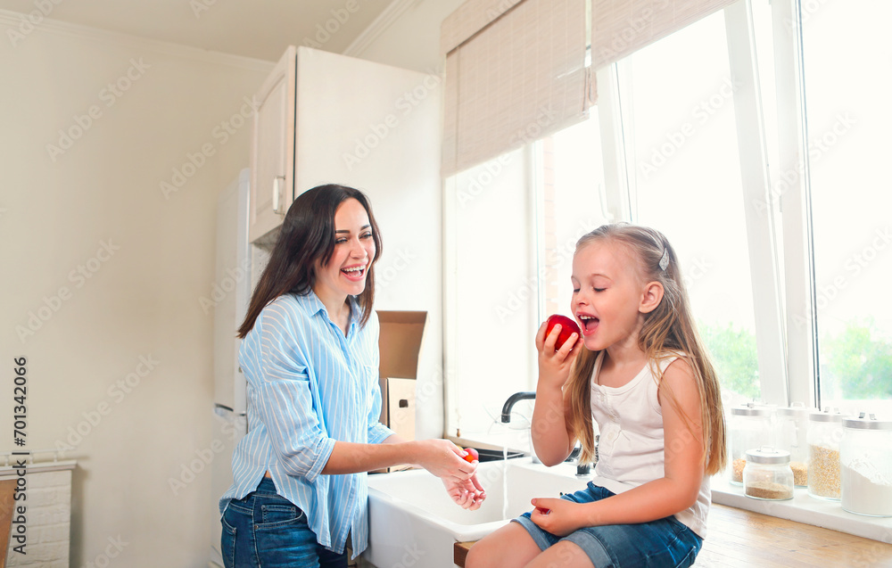 Beautiful little girl with her mother in the kitchen preparing a fresh fruit