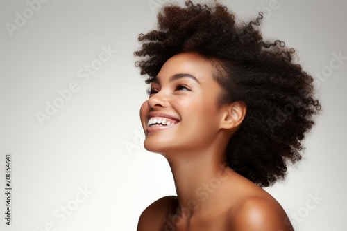 Beauty portrait of african american girl with clean healthy skin on beige background. Smiling dreamy beautiful black woman. Curly hair in afro style